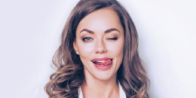 Attractive young woman with long dark blonde hair winking cheekily