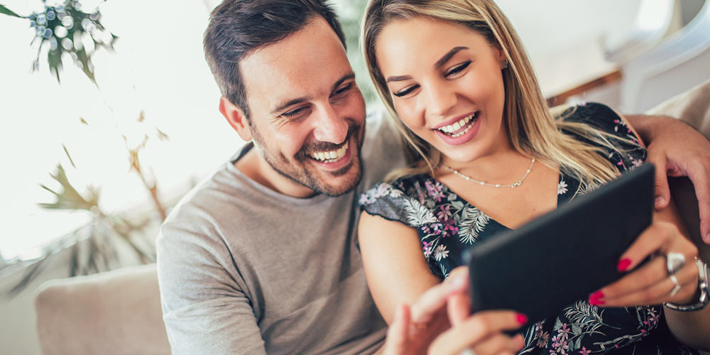 Attractive, young couple chatting on smart device