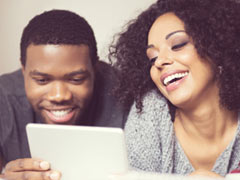 Attractive couple lying on bed browsing member profiles